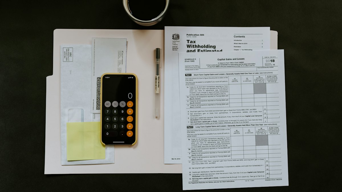 Tax documents, a calculator app and a pen on a desk