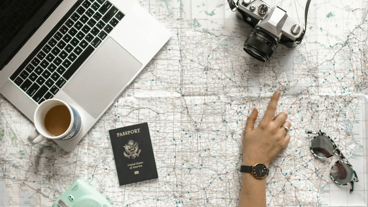Planning a trip on a map with a passport and laptop